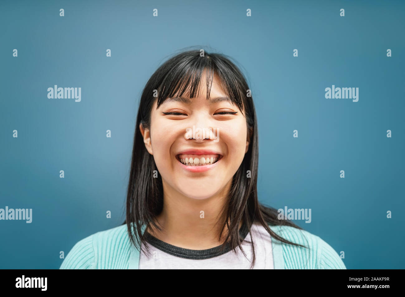 Portrait von jungen asiatischen Mädchen lächelnd an Kamera - Glückliche chinesische Frau Spaß vor blauem Hintergrund posiert Stockfoto