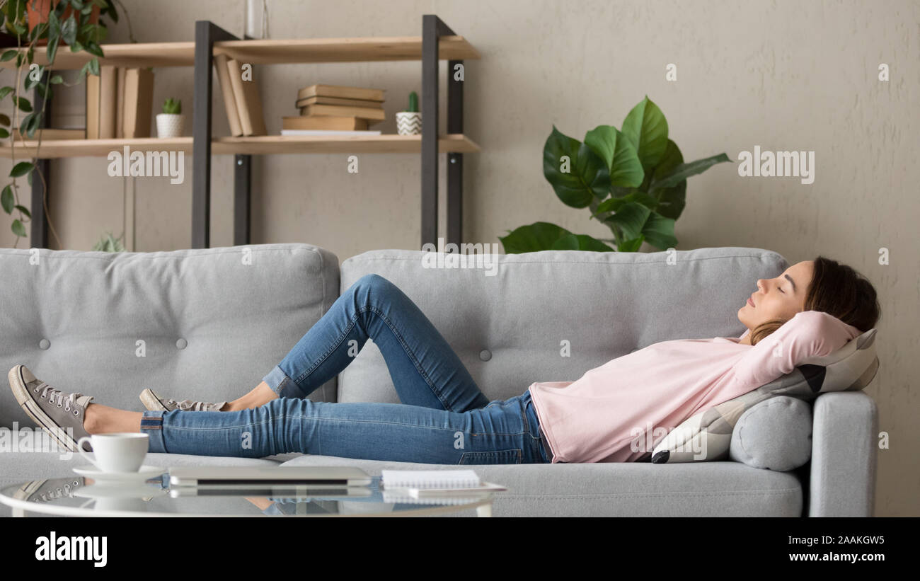 Müde junge Frau zu Hause schlafen auf der gemütlichen Couch entspannen Stockfoto