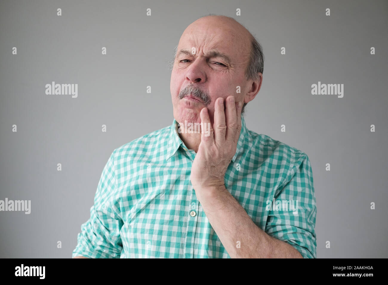 Reifen spanischer Mann Gefühl, Schmerz, seine Wange Holding mit Hand, leiden unter schlechten Zahnschmerzen. Tooth ache Konzept. Stockfoto