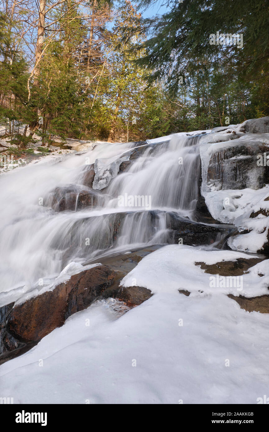 Kaltes Wasser purzelt in den Granitfelsen in Eis und Schnee bedeckt, an der Fischzuchtanstalt fällt in Huntsville, Ontario. Stockfoto