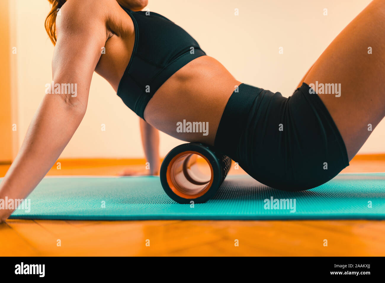 Sportlerin im unteren Rücken massieren mit schaumstoffrolle. Stockfoto