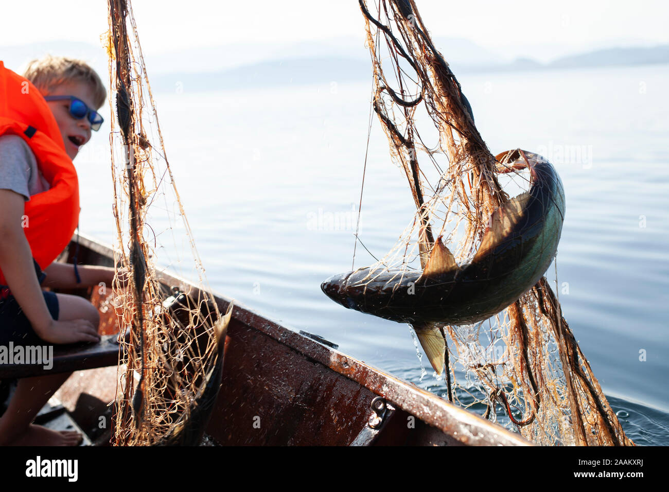 Junge lächelnd an Fisch in einem Fischernetz gefangen Stockfoto