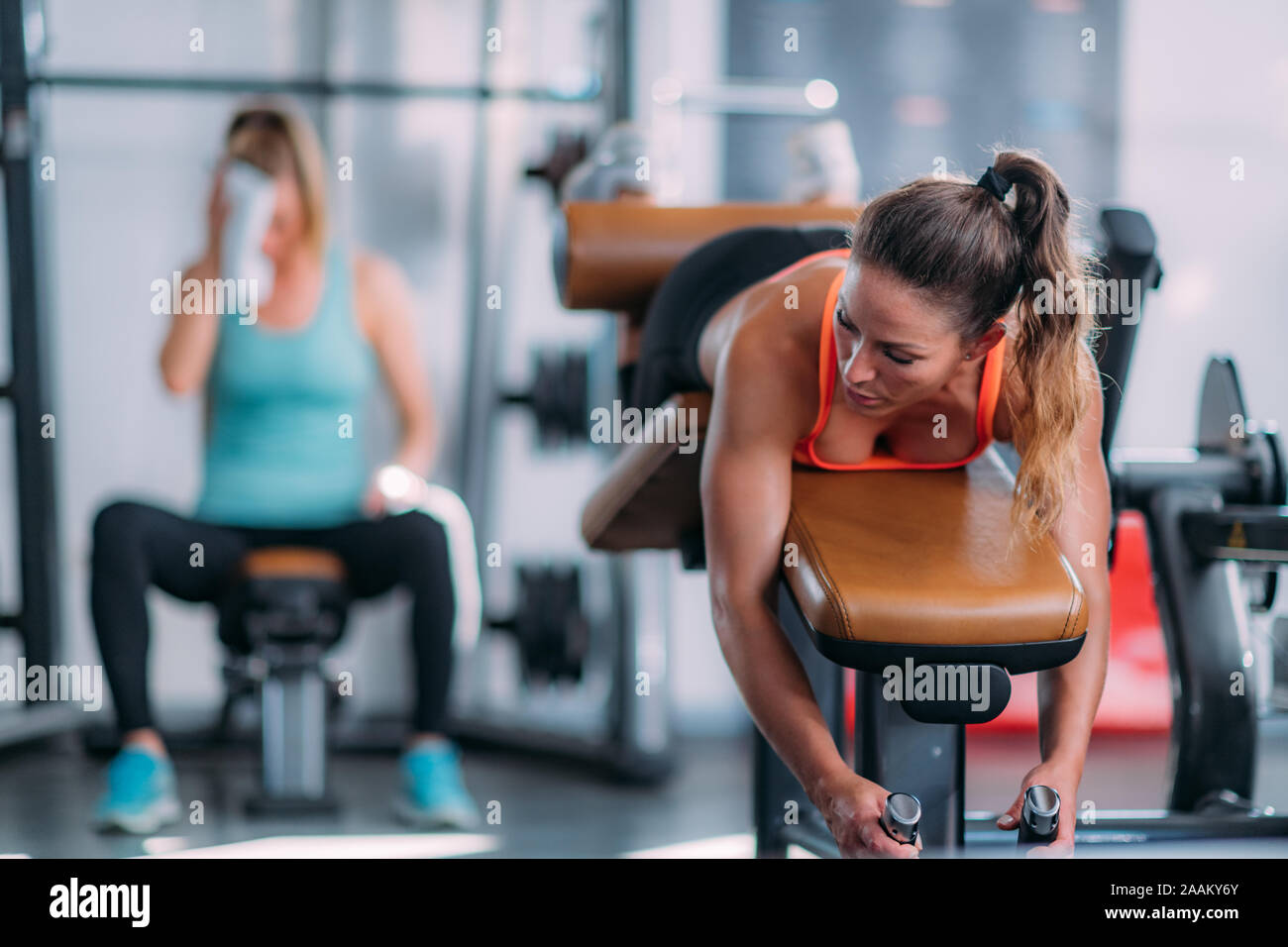 Weibliche Athleten trainieren gestrecktes Bein Sitzbank in der Turnhalle locken. Stockfoto