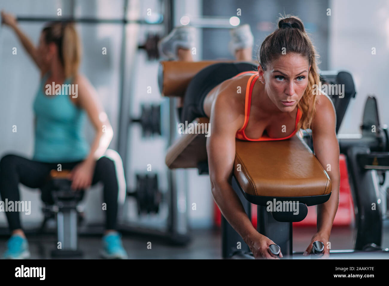 Weibliche Athleten trainieren gestrecktes Bein Sitzbank in der Turnhalle locken. Stockfoto