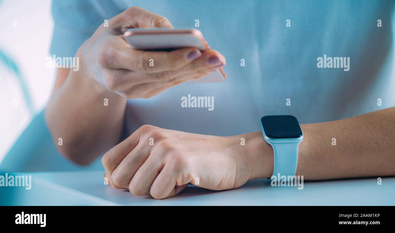 Frau Messen der Herzfrequenz mittels Smart Phone und smart Watch. Stockfoto