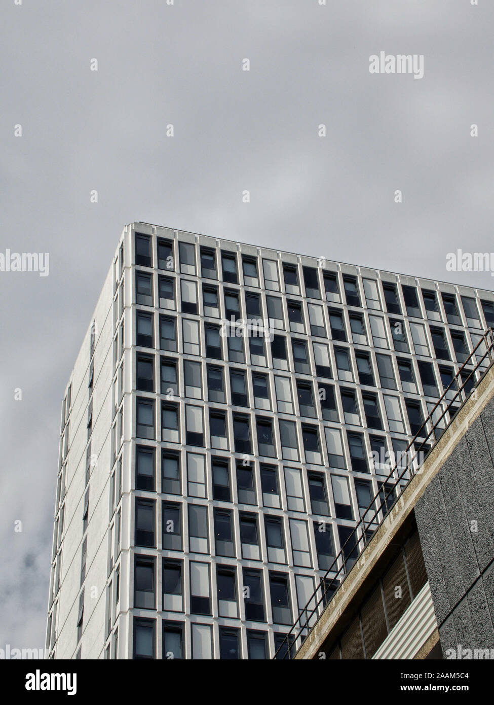 Auf der Suche nach einem modernen, weißen hi Office Block unter einer grauen, wolkenverhangenen Himmel zu Stockfoto