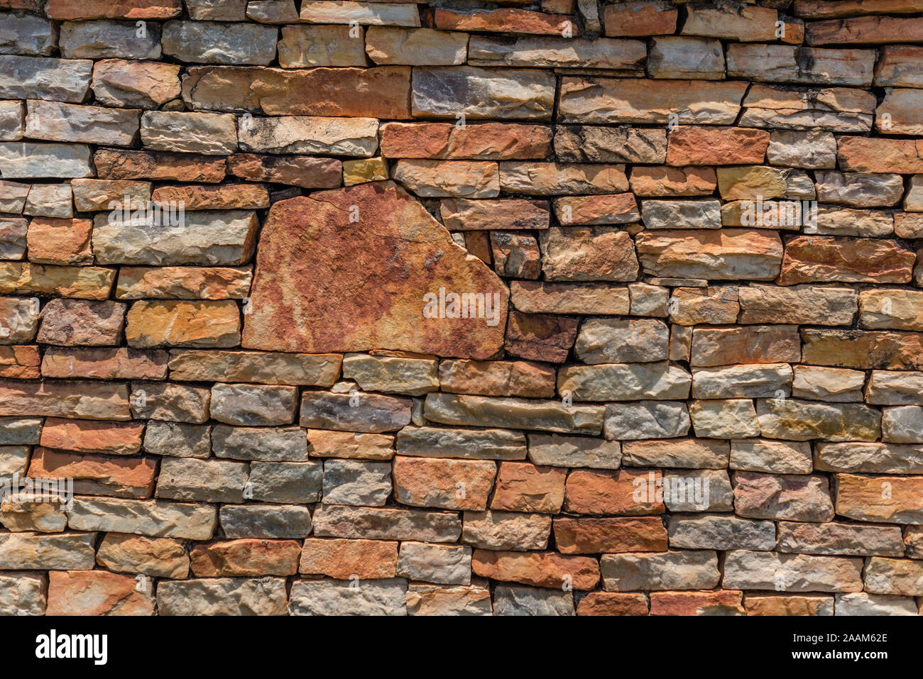 Allgemeiner Hintergrund eines nicht an der Wand der irregulären grungy nicht spitzen Steinen im Sommer Farben in der Sonne mit ihren Schatten auf die Steine Stockfoto
