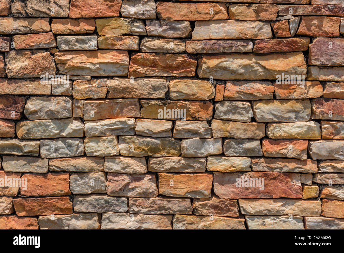 Allgemeiner Hintergrund eines nicht an der Wand der irregulären grungy nicht spitzen Steinen im Sommer Farben in der Sonne mit ihren Schatten auf die Steine Stockfoto