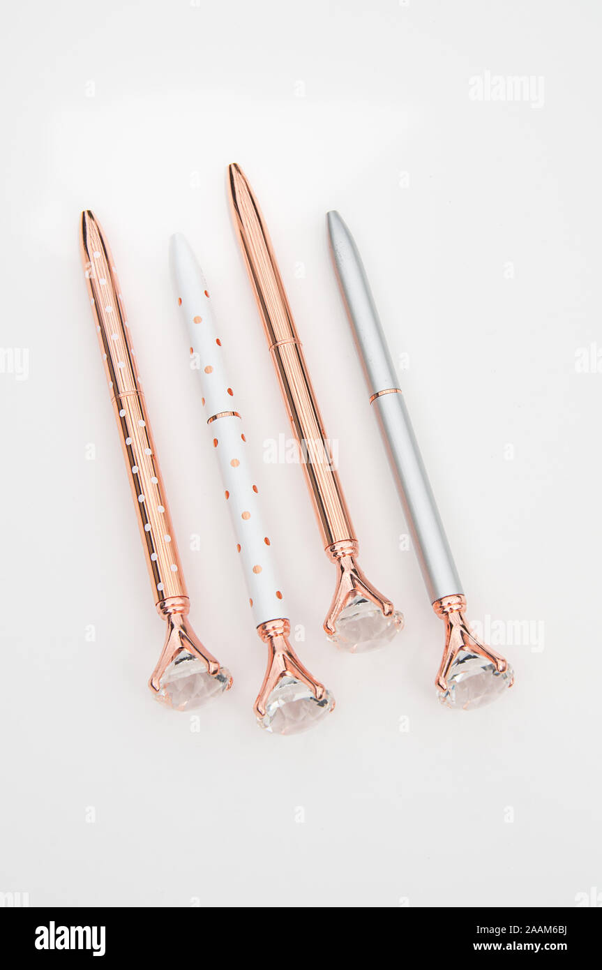 Set mit 4 Stiften Tinte auf einem hellen Hintergrund isoliert. Fancy Kugelschreiber in Rose Gold, Weiß und Silber, einige mit Polka Dots. Business still life gr Stockfoto