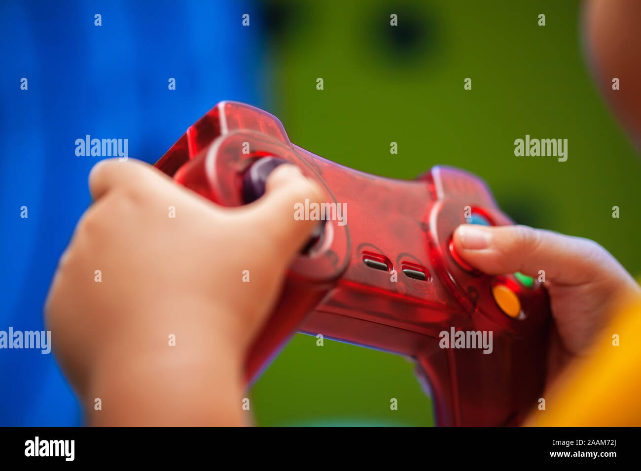 Nahaufnahme der Hand ein Kind hält ein Video Game Controller während des Spielens ein buntes Spiel auf dem Bildschirm. Stockfoto