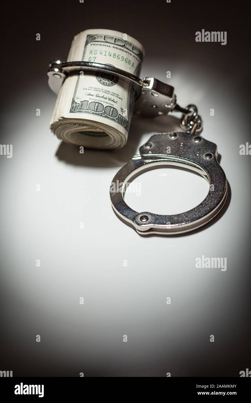 Handschellen Gesperrt auf Rolle von einem Hundert-euro-Scheine unter Spotlight. Stockfoto