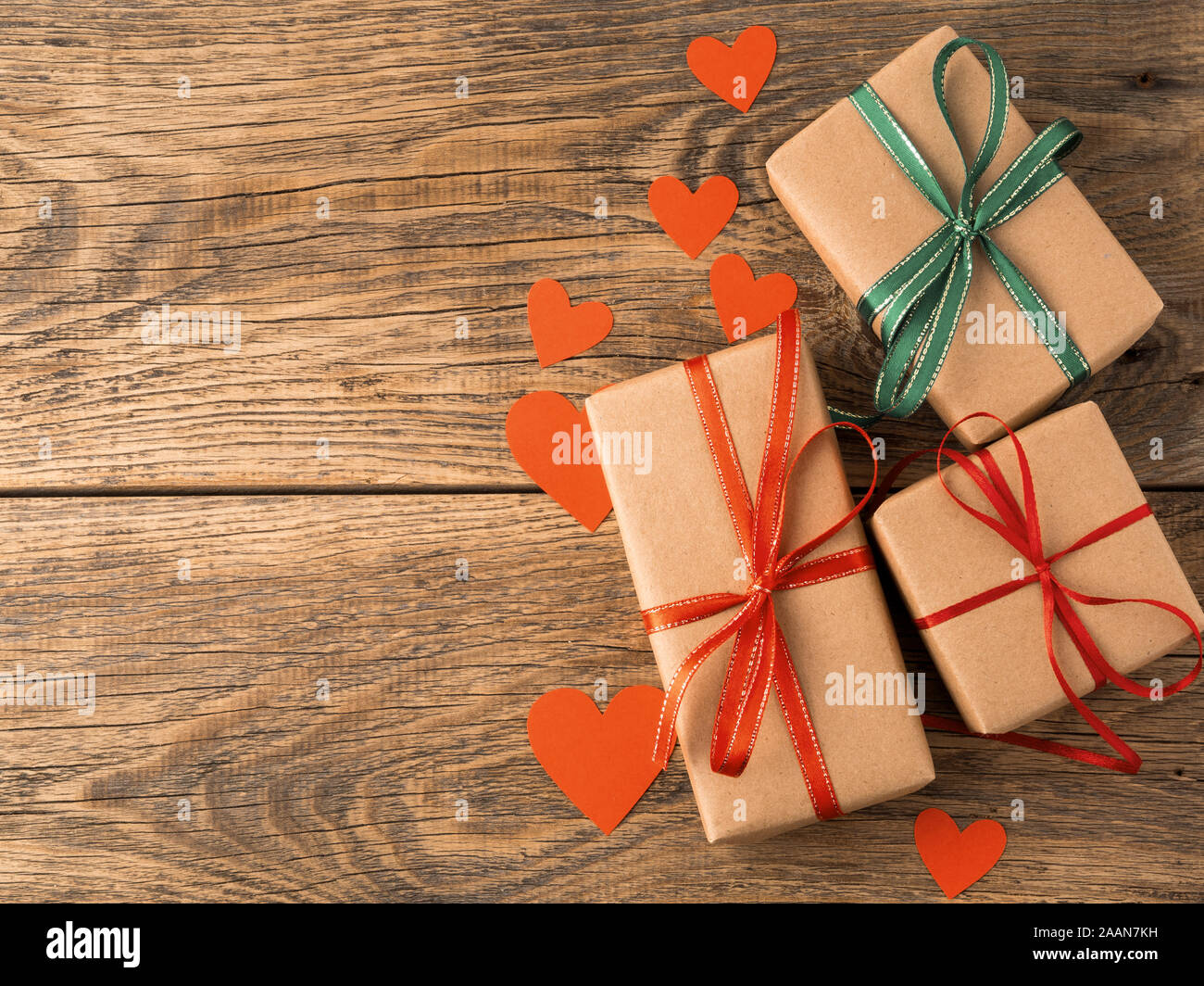 Valentinstag Hintergrund. Geschenke verpackt mit Kraftpapier braun Papier, mit roten Bändern, Herz im Alter von rustikalen Vintage alte hölzerne Hintergrund Stockfoto