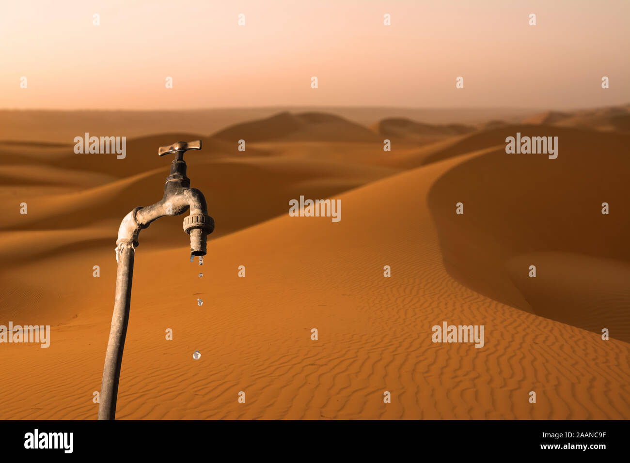 Wasserhahn, tropft und Wüste im Hintergrund, Konzept der Austrocknung des Planeten und Wasserknappheit Stockfoto