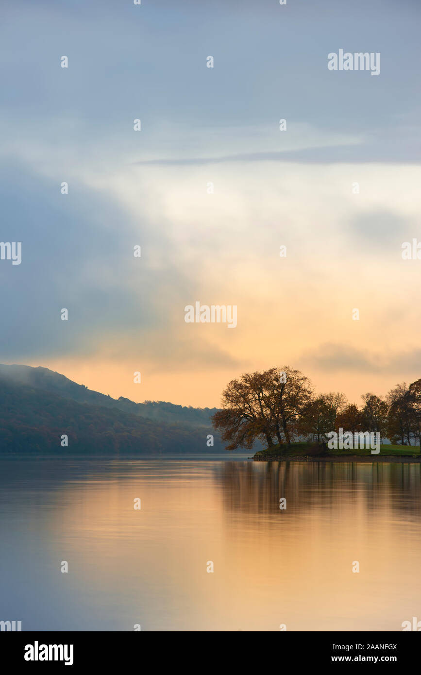 Schönen Sonnenaufgang Landschaft über Coniston Water im Herbst mit Nebel und Wolken wispy Stockfoto