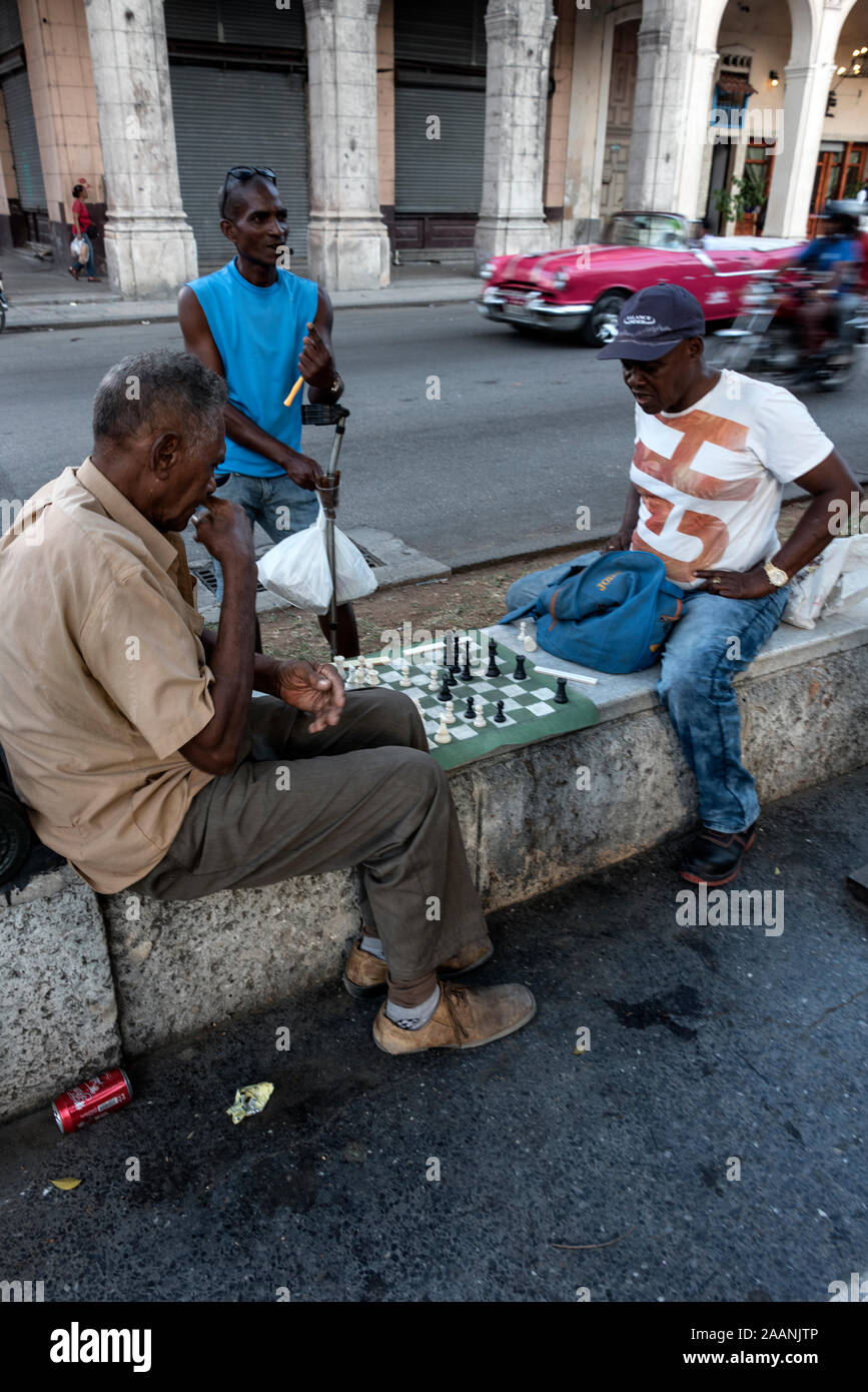 Die einheimischen Männer sitzen auf Marmorsitzen und spielen auf dem Passeo del Prado, einem langen Boulevard in Havanna, Kuba, eine Partie Schach. Der Boulevard, gesäumt mit Bronze Stockfoto