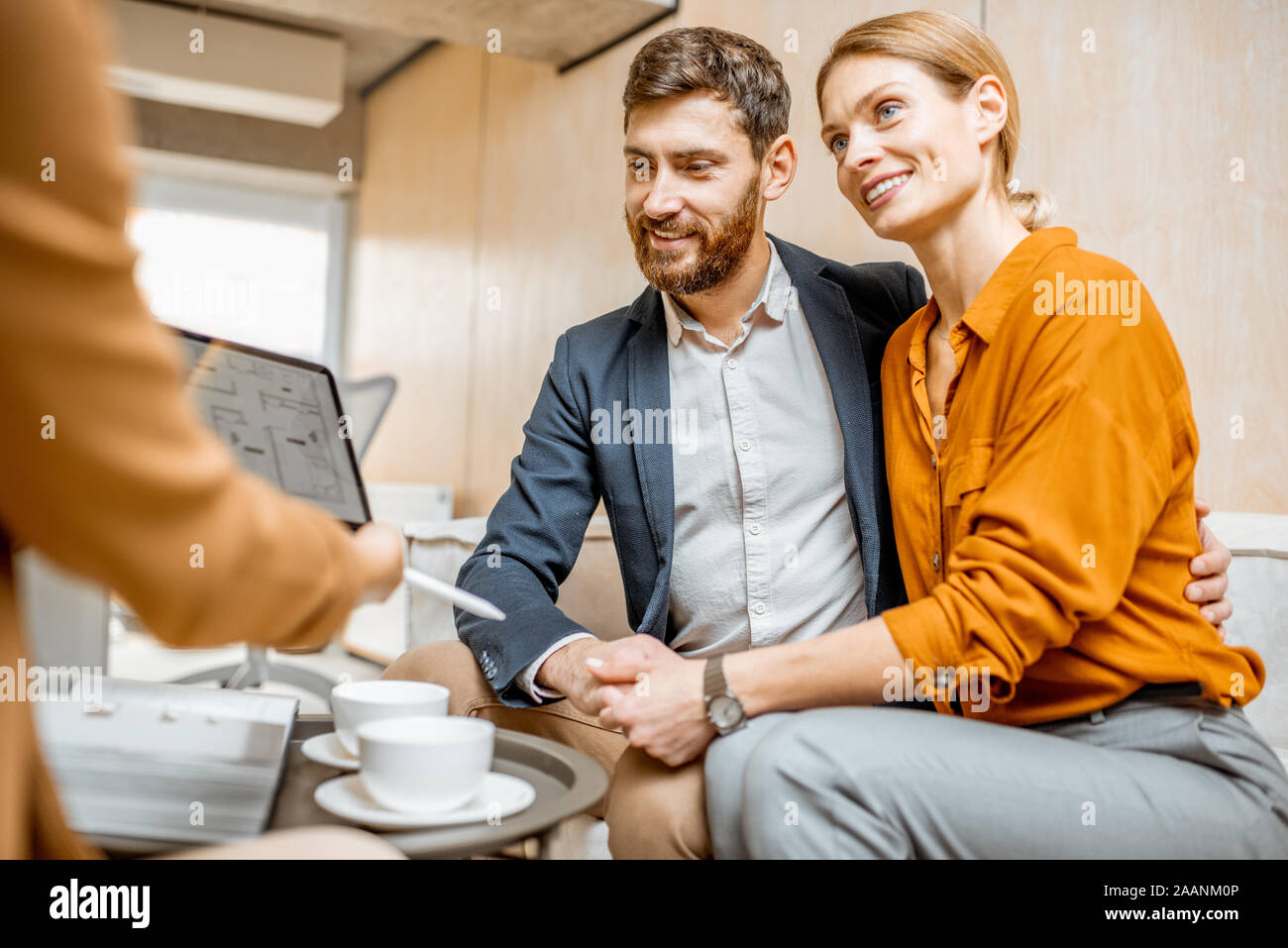 Jung und Paar schöne Wahl, ein neues Haus zu kaufen, wenn er auf die Projekte mit einem Sales Manager im Büro von Immobilien Agentur Stockfoto