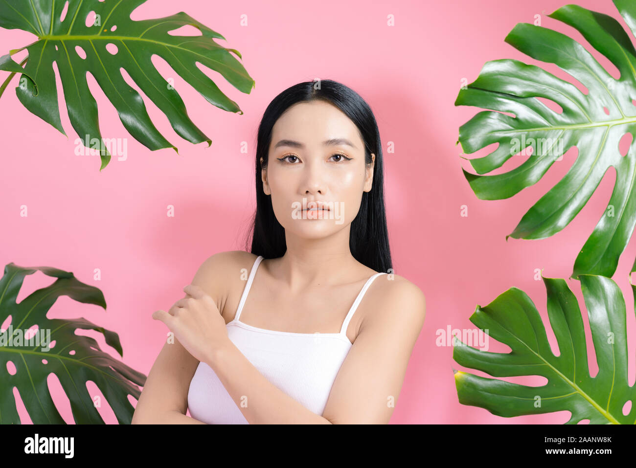 Porträt der schönen Asiatin in tropischen Blättern. Konzept der natürlichen Kosmetik und Hautpflege Stockfoto