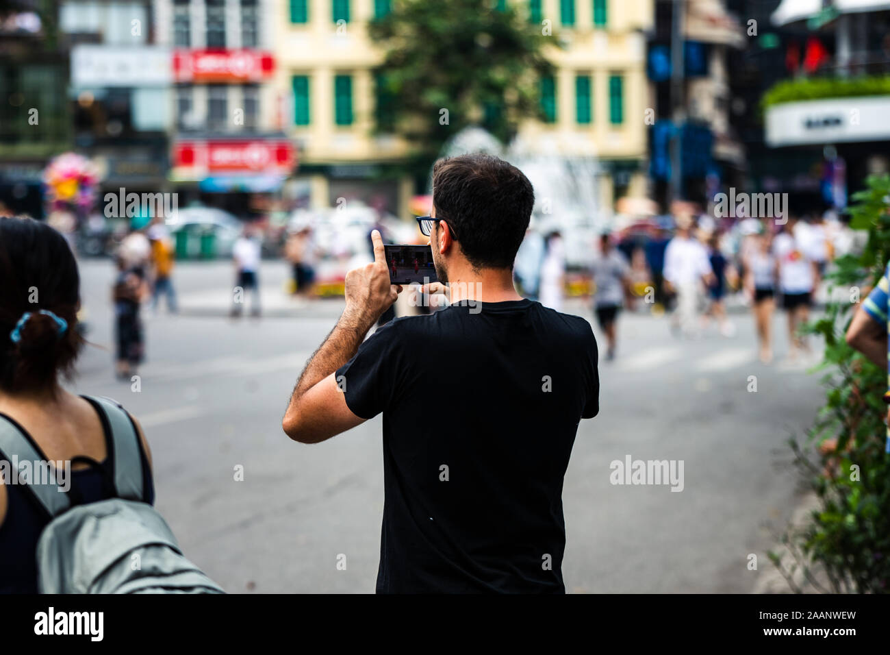 Eine stolze und glückliche kaukasischen Vater seine Söhne Tanz Performance auf einem Smartphone in einer asiatischen Stadt an einem heißen Tag Stockfoto