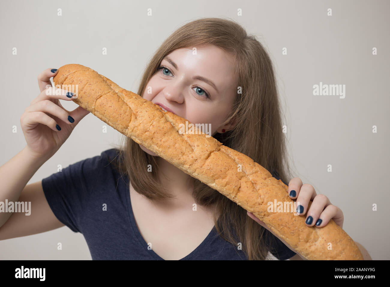 Junge kaukasische Frau isst französisches Baguette Stockfoto