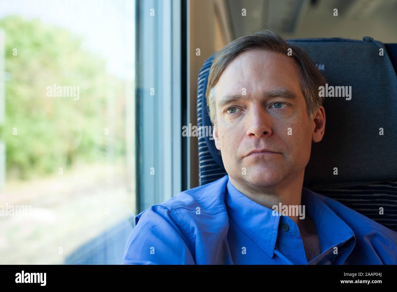 Kaukasische Mann in den 40er Jahren trägt blaue Shirt sitzen auf pendlerzug Stockfoto