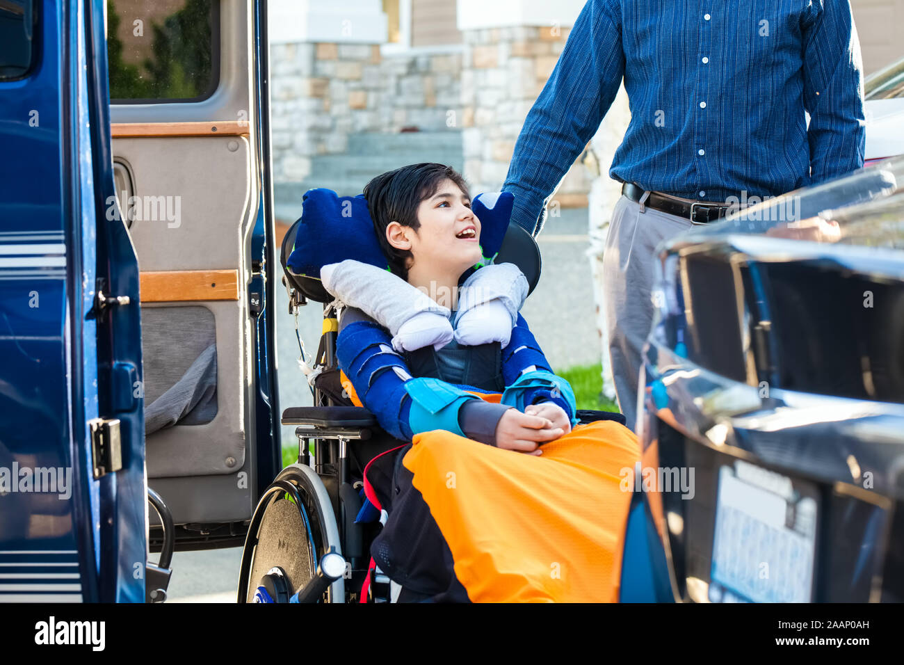 Besondere Bedürfnisse elf Jahre alten Jungen im Rollstuhl im Freien bereit am Fahrzeug Rollstuhllift mit Vater zu fahren Stockfoto