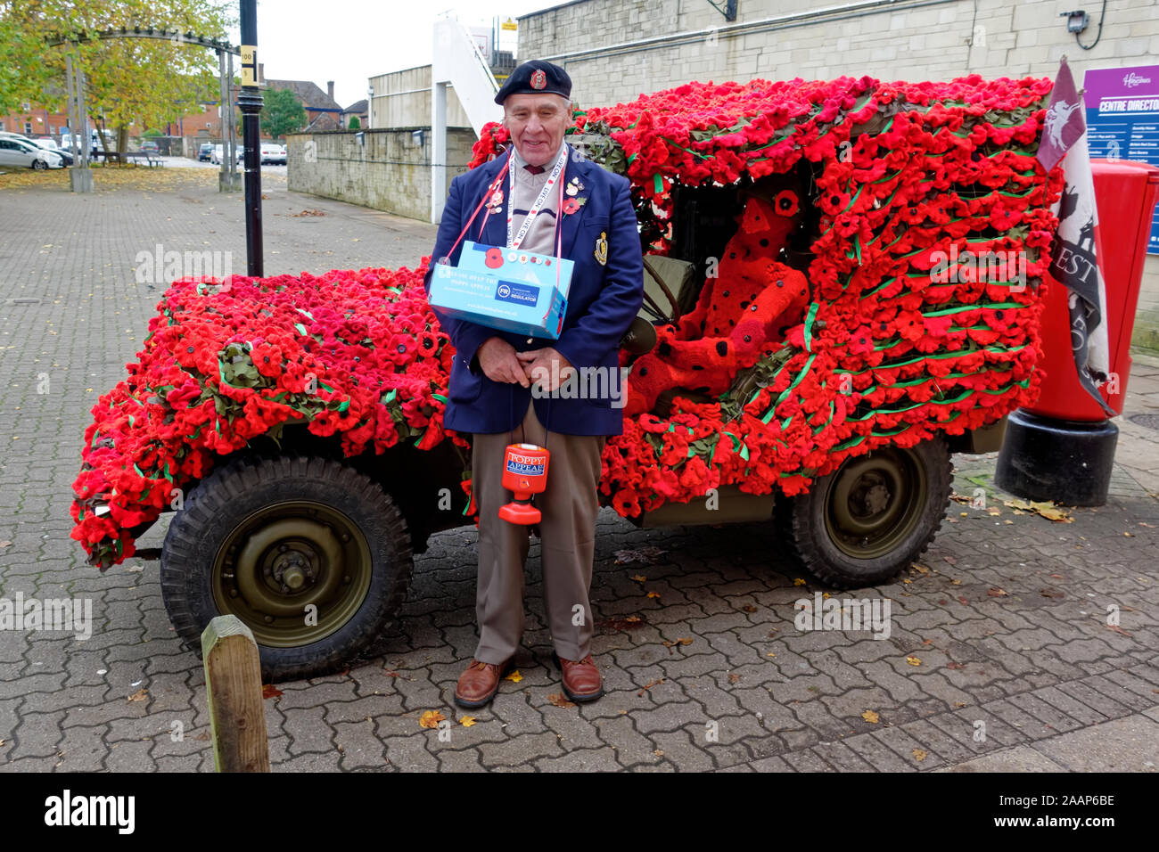 Poppy Verkäufer Arthur Smith aus Heytesbury steht vor seinem WW2 American Military Jeep mit gestrickten Mohnblumen geschmückt Stockfoto
