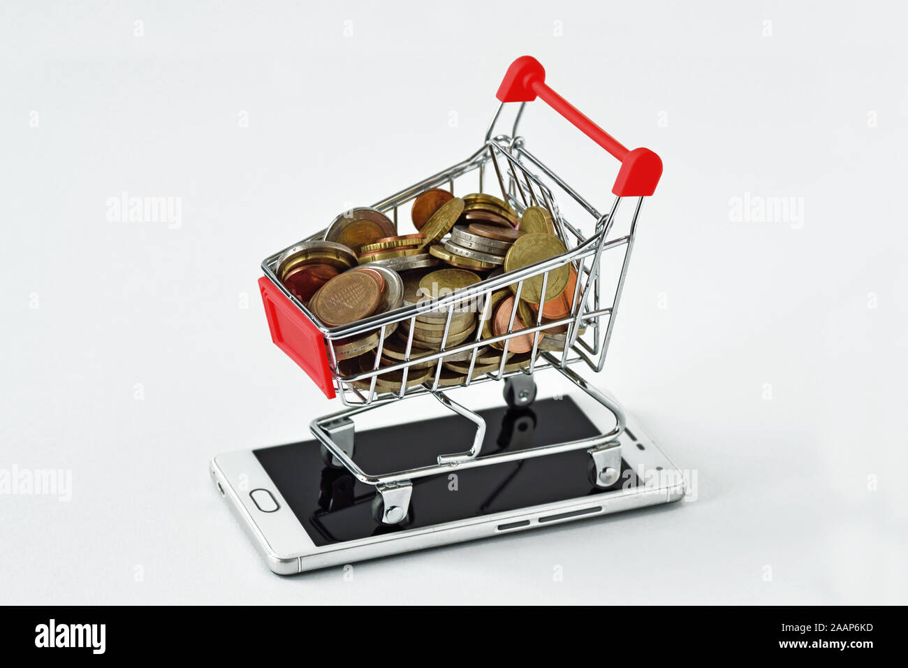 Warenkorb voller Münzen auf Handy - Begriff des e-Commerce und Mobile Payment Stockfoto