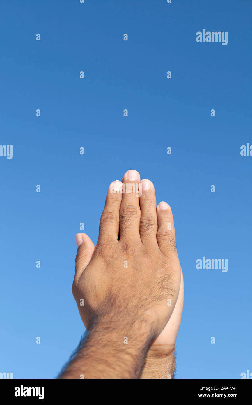 Junger Mann die gefalteten Hände vor blauem Himmel Stockfoto