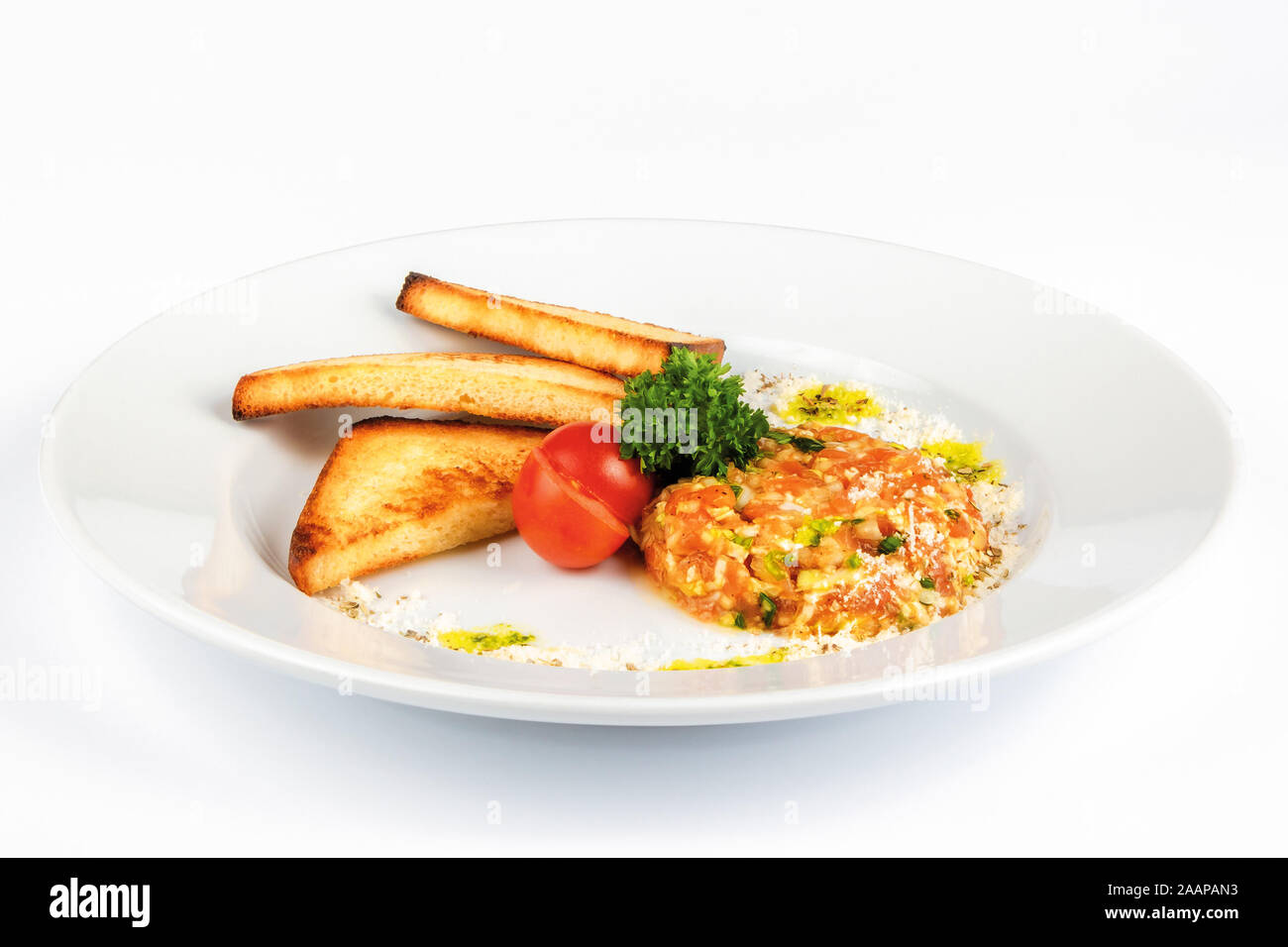 Beef Steak Tartar mit Croutons. rohes Rindfleisch mit Zwiebeln auf dem weißen Teller dekoriert mit kirschtomate. Seitenansicht Stockfoto