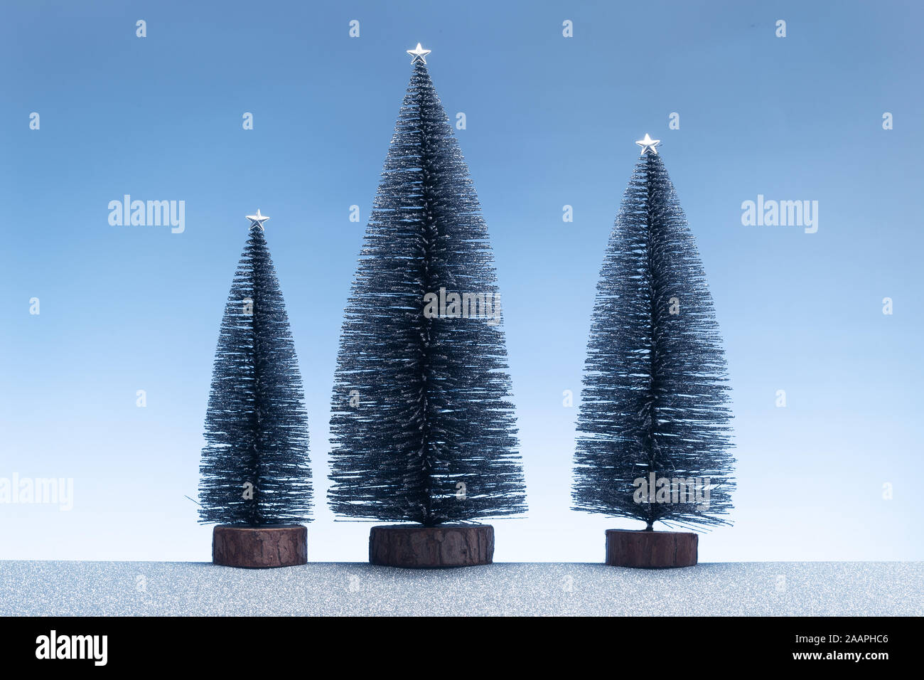 Weihnachten Hintergrund. Minimalistische Szene mit Miniatur Tannen und glitzerndes Silber Masse und blauer Himmel Stockfoto