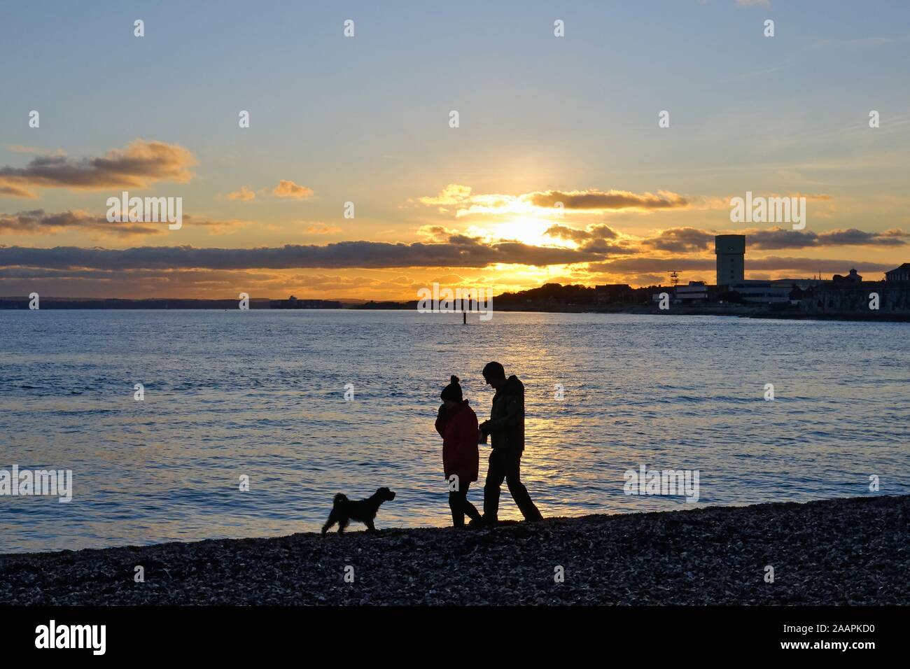 Silhouette von ein paar wenige ein Hund am Strand von Portsmouth vor dem Hintergrund einer im Winter Sonnenuntergang, Hampshire England Großbritannien Stockfoto