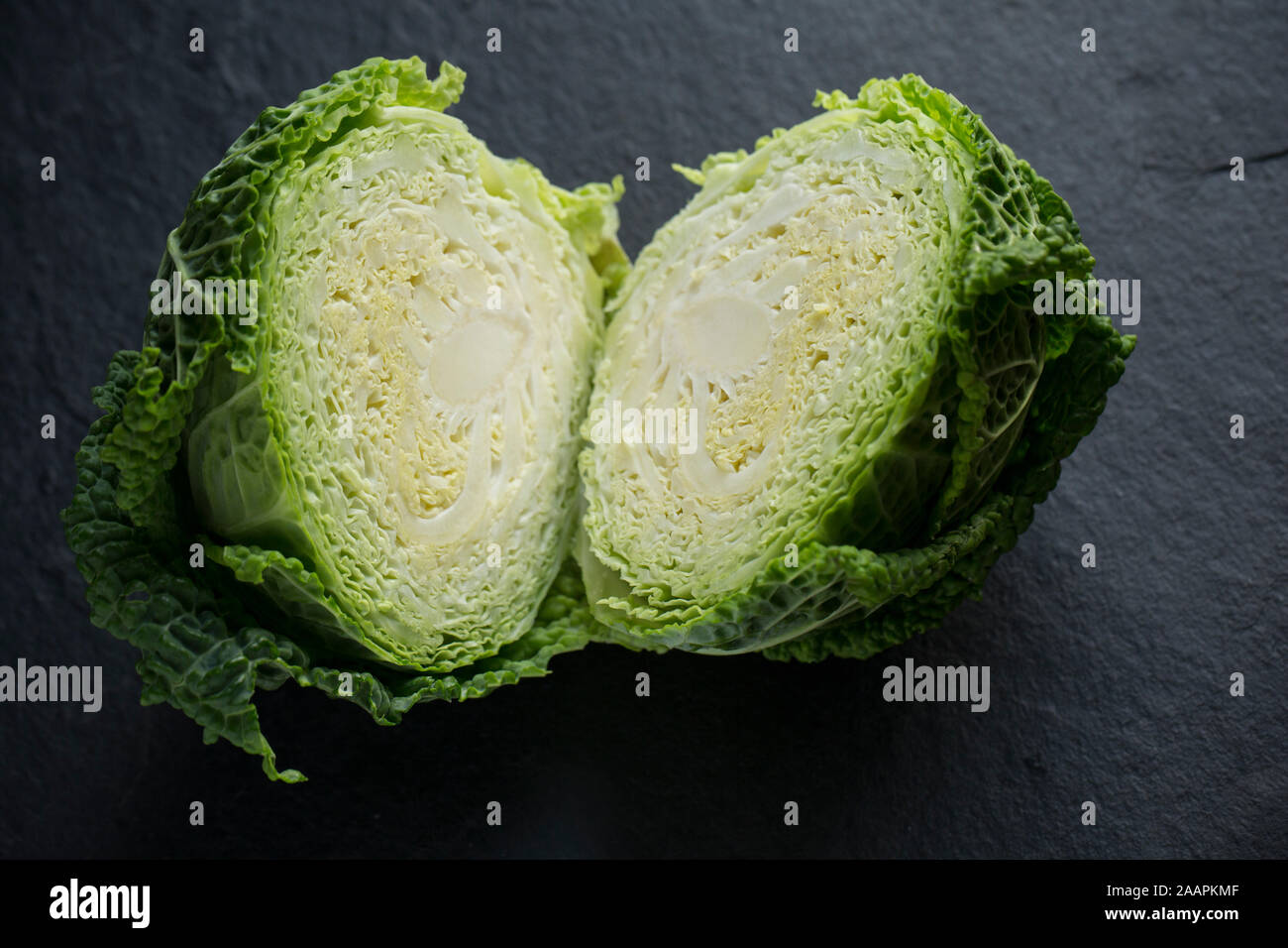 Eine Halbierung der Britischen Wirsing gekauft von einem Supermarkt in Großbritannien. Auf dunklem Schiefer Hintergrund fotografiert. England UK GB Stockfoto