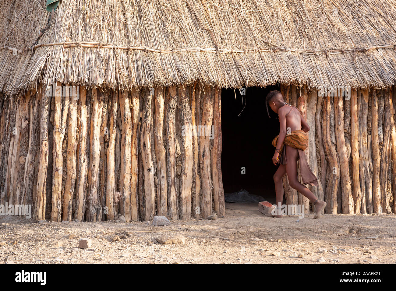 Ein Kind geht in eine Hütte in einem Himba Stammes- dorf in Namibia, Afrika Stockfoto