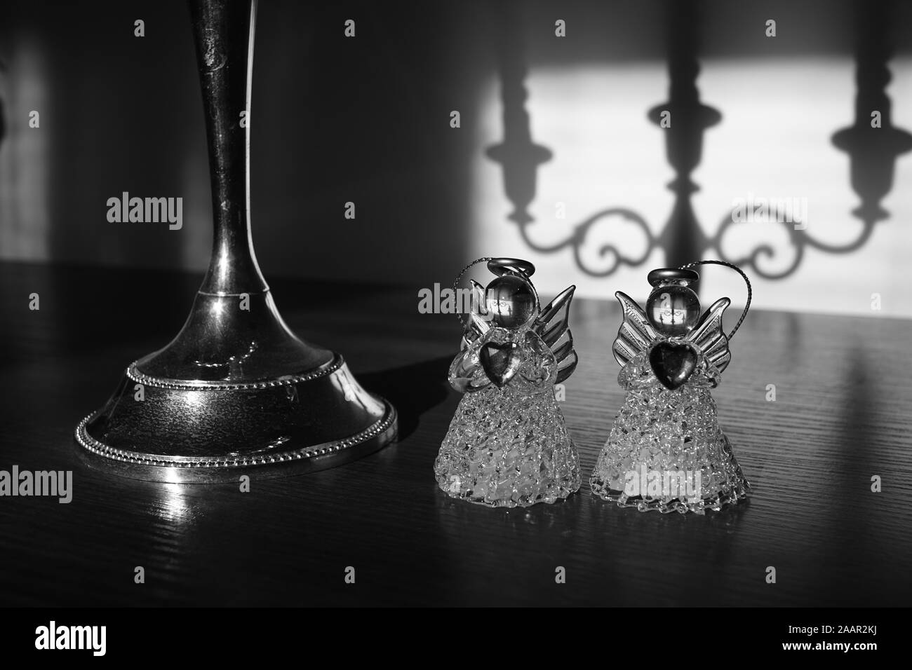 Zwei kleine Statuen von Engeln, die in der Nähe von Vintage Leuchter. Schwarz-weiß Foto. Stockfoto