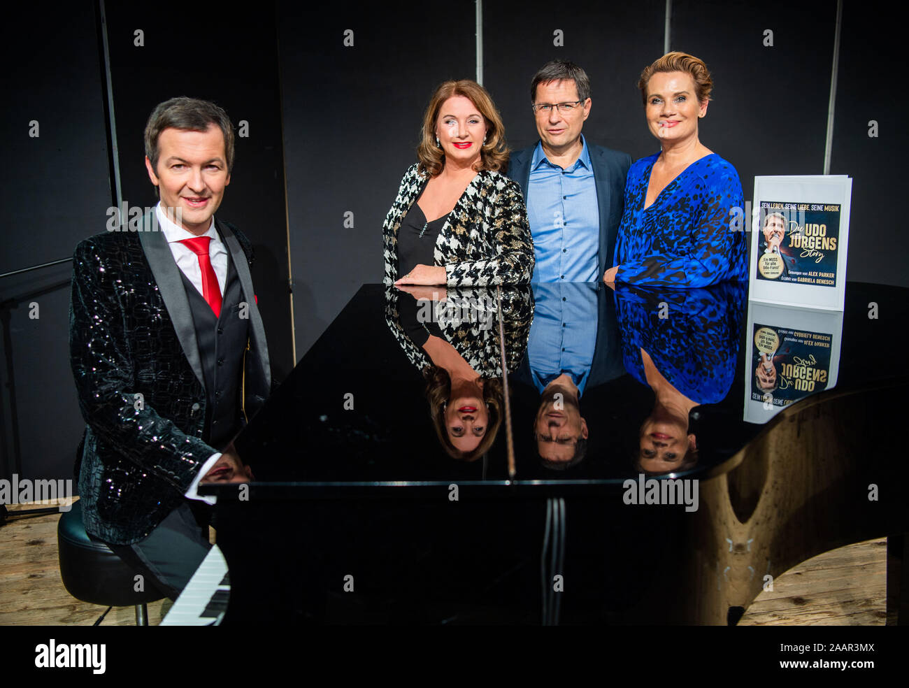 München, Deutschland. 23 Nov, 2019. Alex Parker (L-R), Pianist, Gabriela Benesch, Produzent, Erich Furrer, Direktor, und Jenny Jürgens, Schauspielerin, Sängerin und Tochter von Udo Jürgens, stand auf der Bühne eines Theaters an einem Klavier anlässlich der Performance "Udo Jürgens Geschichte". Credit: Lino Mirgeler/dpa/Alamy leben Nachrichten Stockfoto