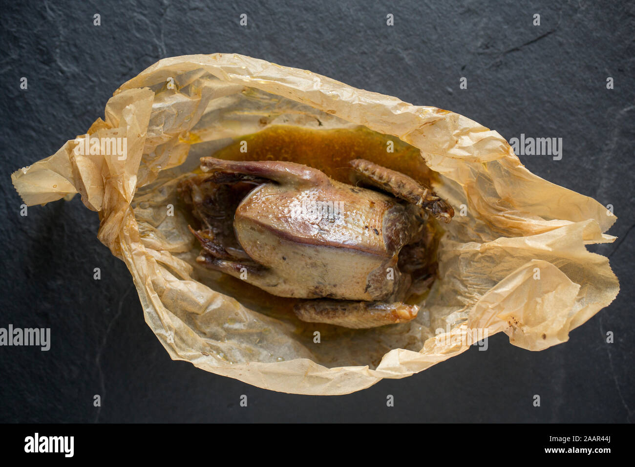 Eine Ringeltaube, Columba Palumbus, für den Pflanzenschutz erschossen wurde, die in der Papier geröstet wurde, en Papillote. Die britische Bevölkerung aus Holz pige Stockfoto