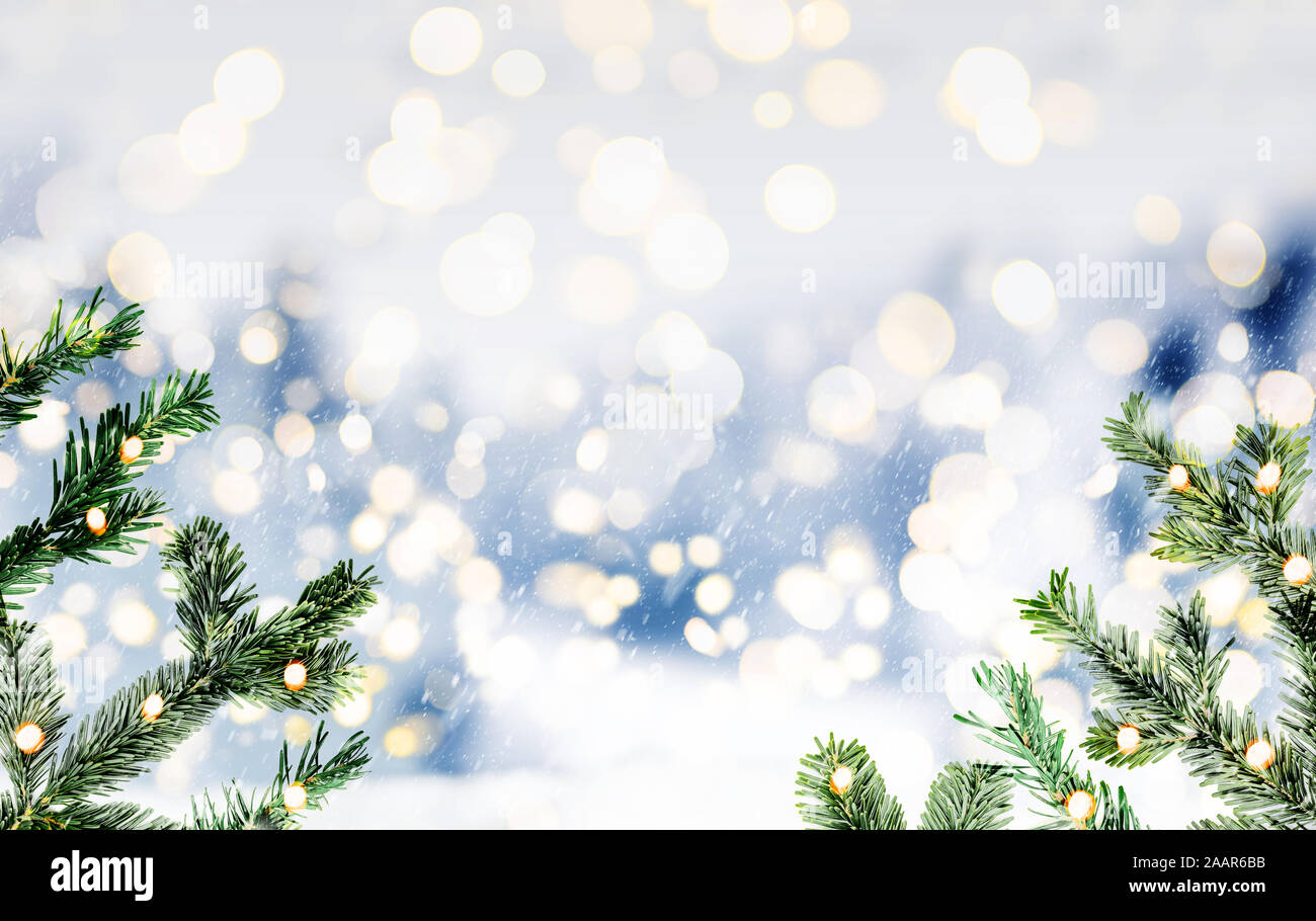 Blurry schneereiche Winter oder Weihnachten Hintergrund mit Tannen Zweigen und glühenden kreisrunden Licht Stockfoto