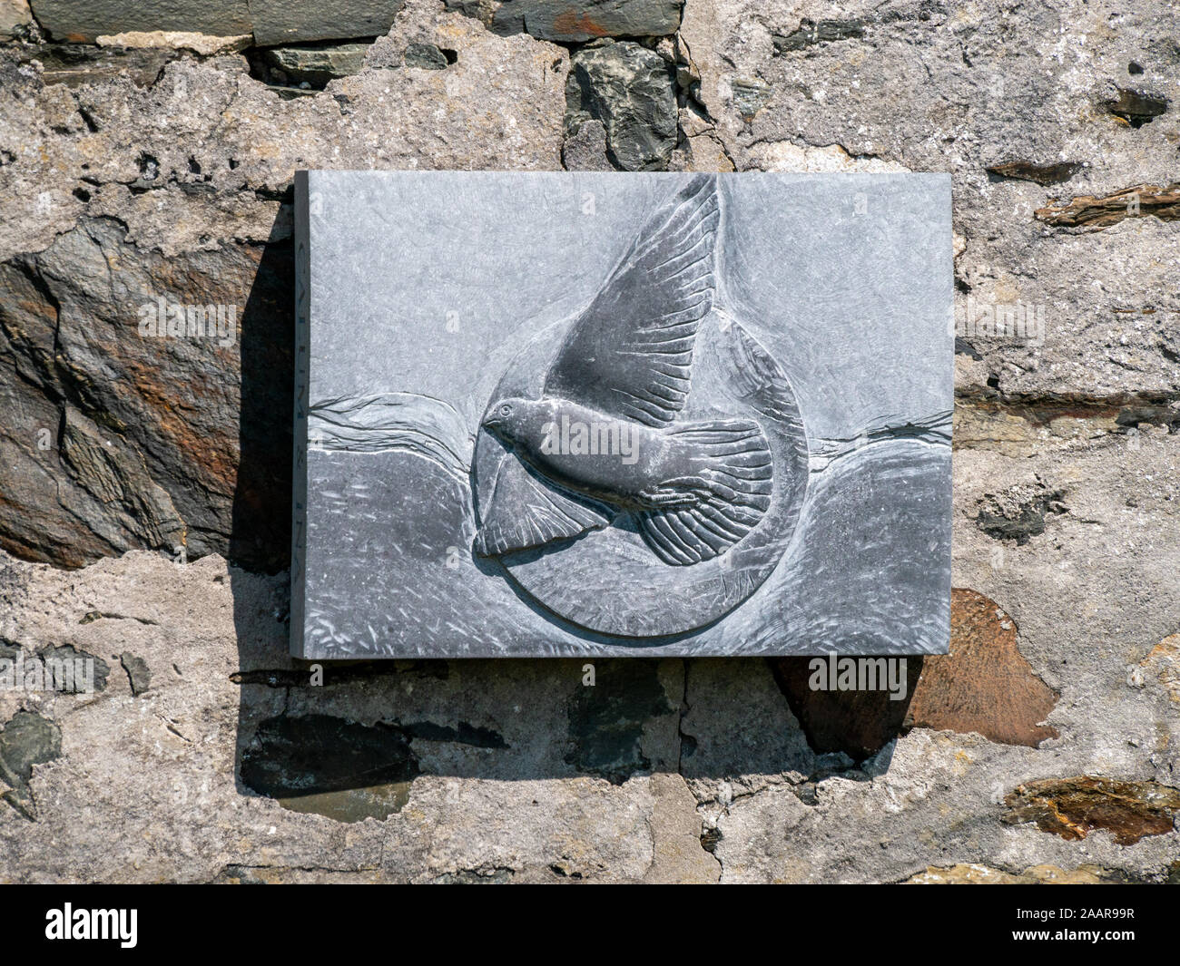 Geschnitzte Schiefer wall Plaque mit fliegenden Vogel (wahrscheinlich rock dove) an der Wand der Hütte durch RSPB, Insel Oronsay, Colonsay, Schottland, Großbritannien Stockfoto