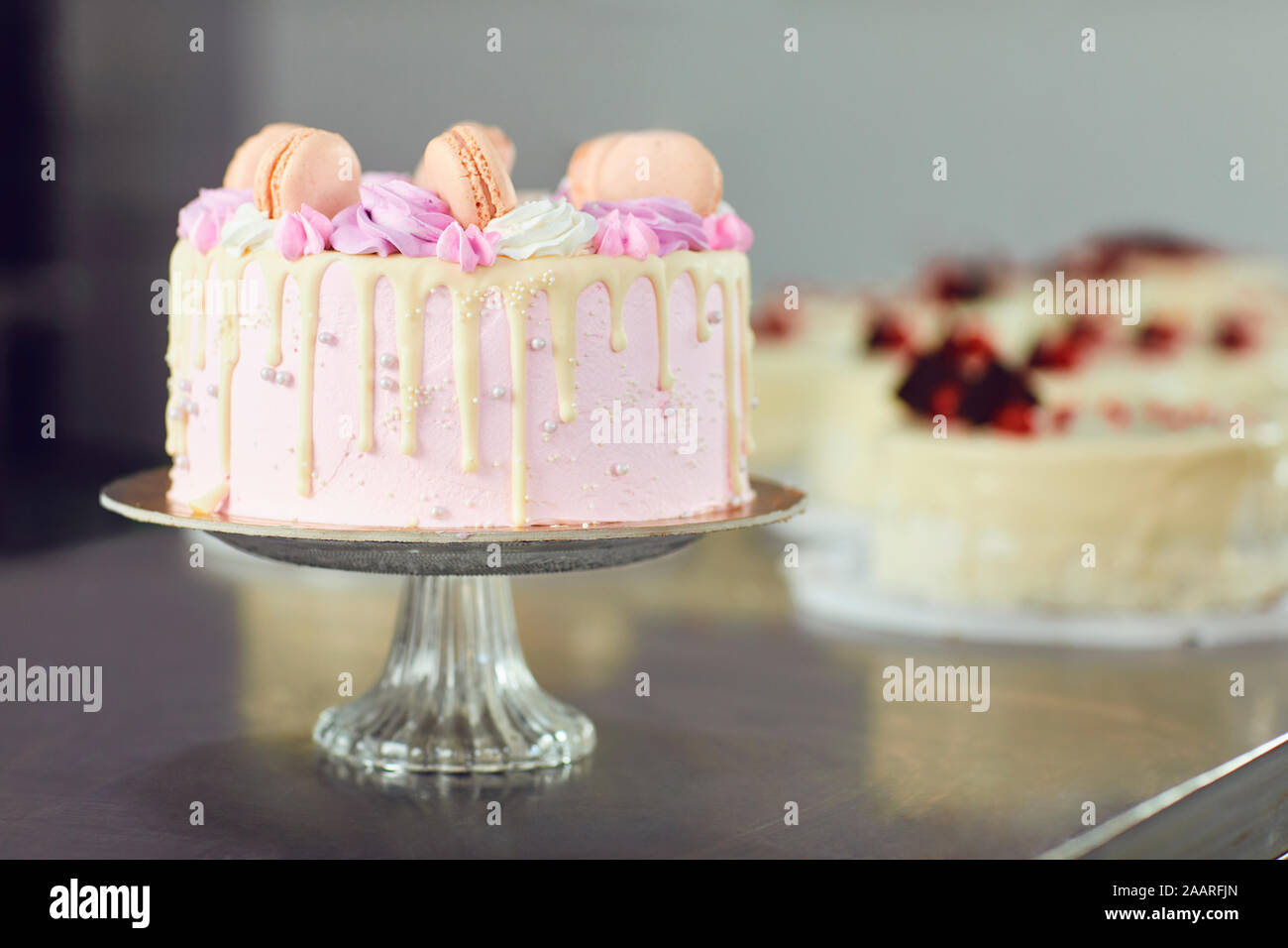 Rosa Kuchen mit Makronen auf dem Tisch eingerichtet. Stockfoto