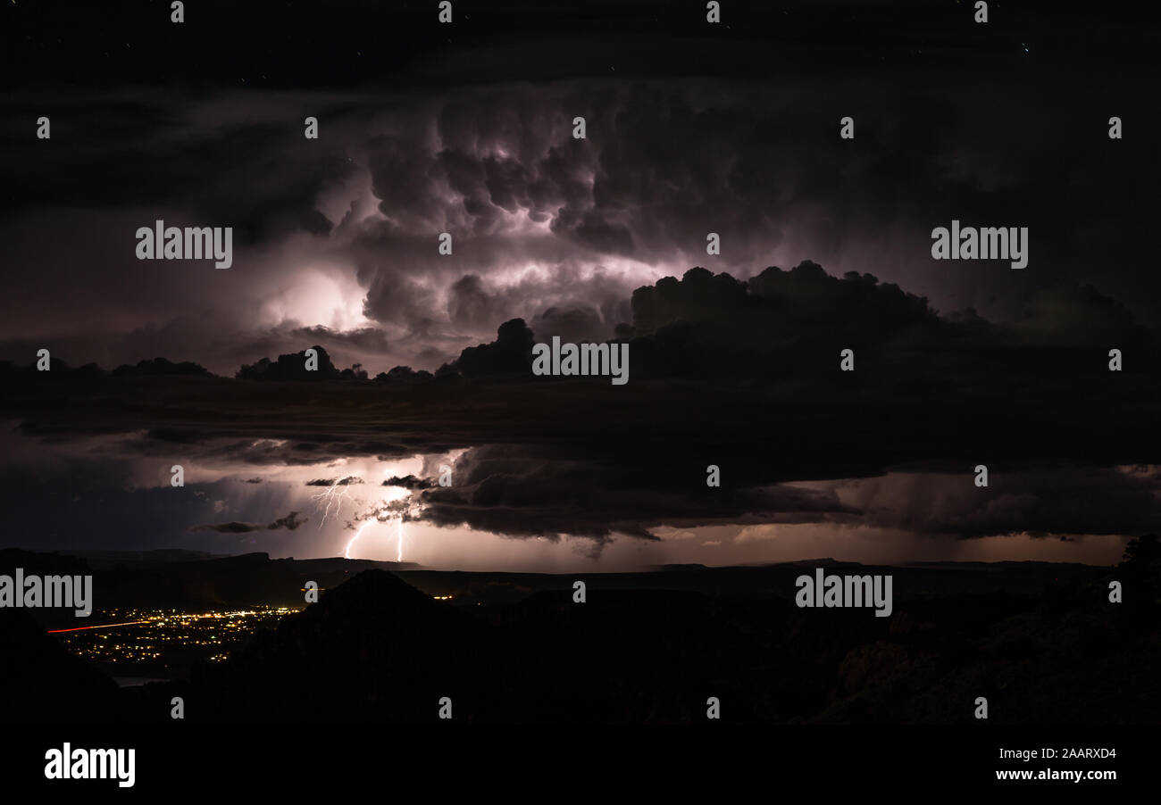 Unwetter mit Überschwemmungen und Blitz in der Wüste von Utah in der Nähe von Moab. Entfernte Blitze erhellen die Nacht und massive Gewitterwolken ove Stockfoto