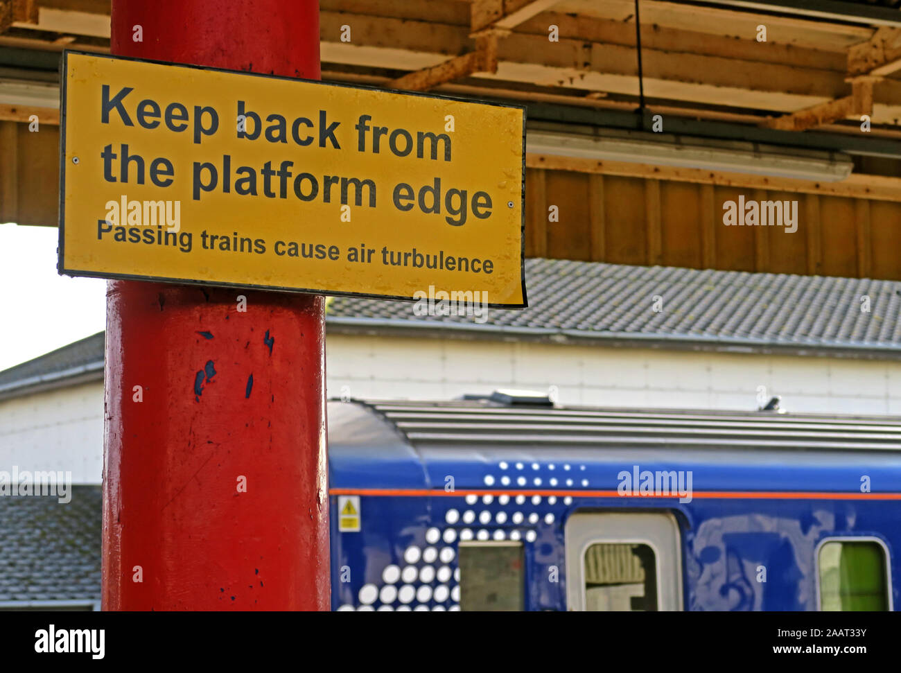 Zurück von der Bahnsteigkante, gelbes Schild, vorbeifahrende Züge verursachen Luftverwirbelungen, auf der Plattform, Hochgeschwindigkeitszüge Stockfoto