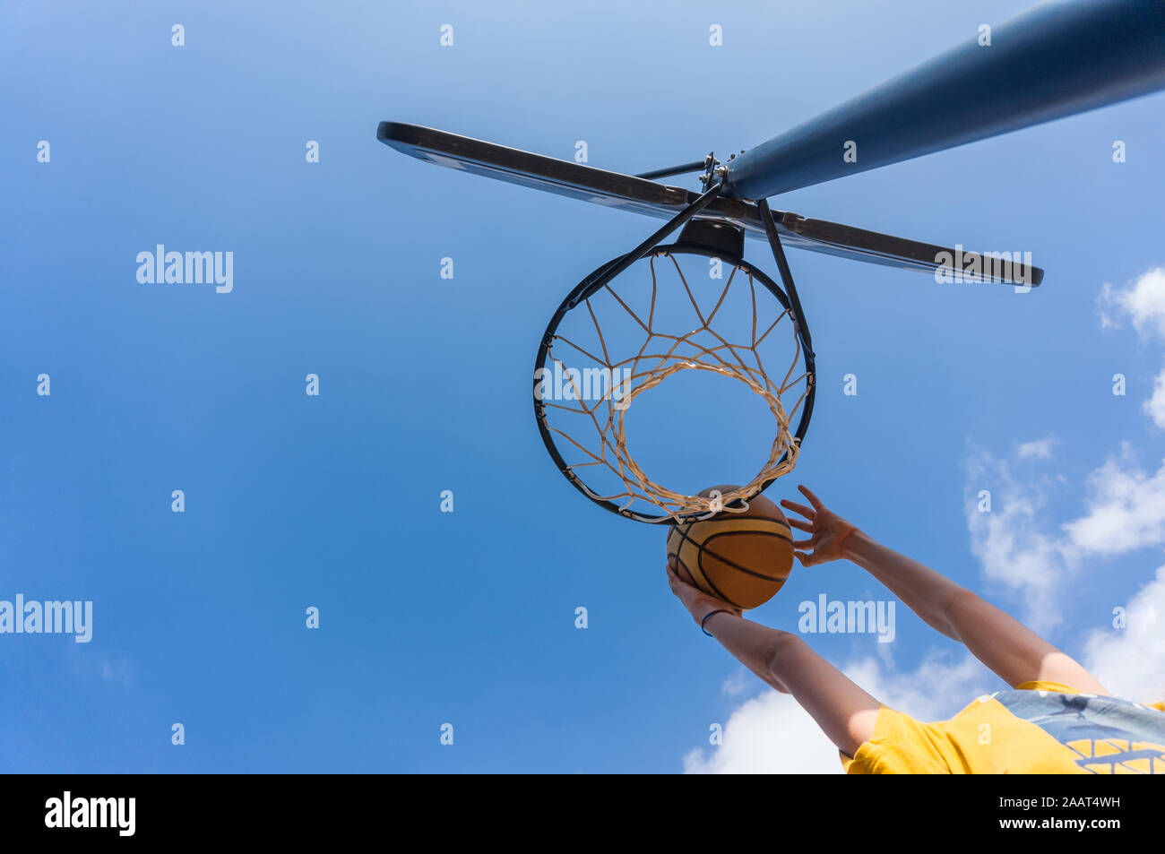 Slam Dunk im Basketball im Freien mit blauem Himmel Stockfoto