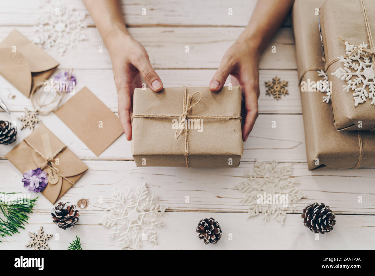 Nahaufnahme von Händen Frau vorhanden Geschenkbox auf Holztisch mit Weihnachten Dekoration. Stockfoto