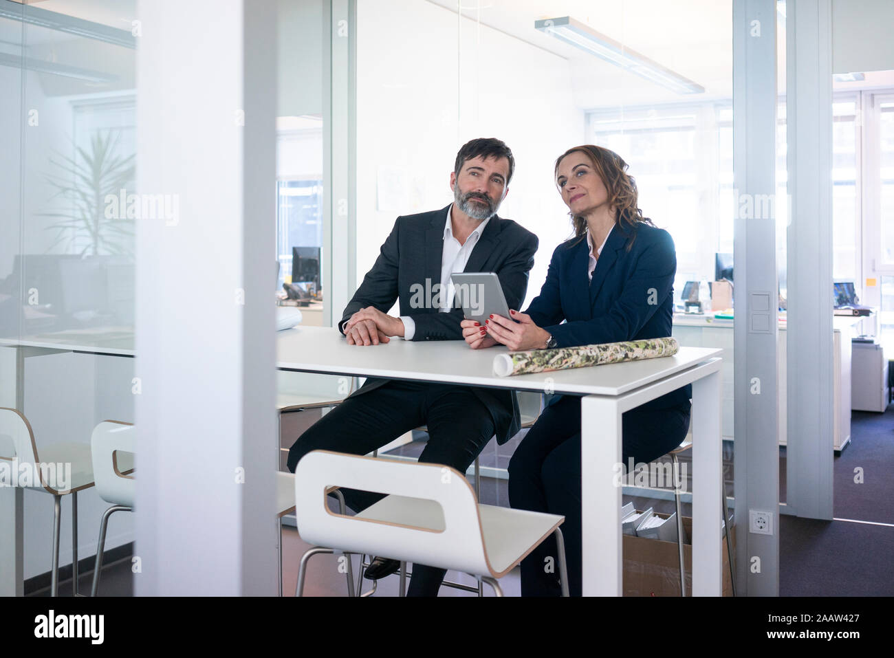 Geschäftsfrau und Geschäftsmann mit Tablet-PC auf dem Schreibtisch im Büro zu sitzen Stockfoto