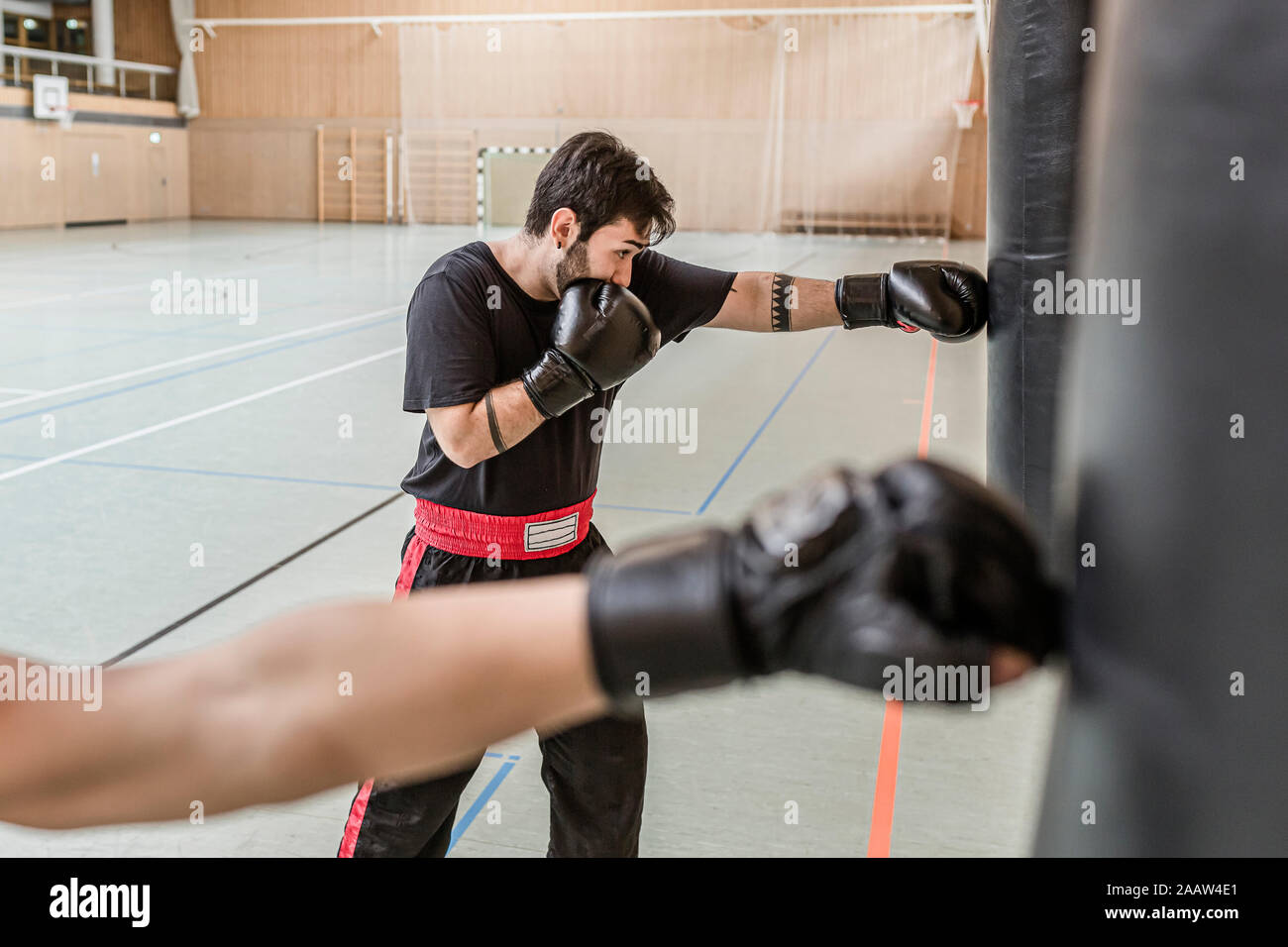 Trainer und Boxer üben an Boxsäcke in der Sporthalle Stockfoto