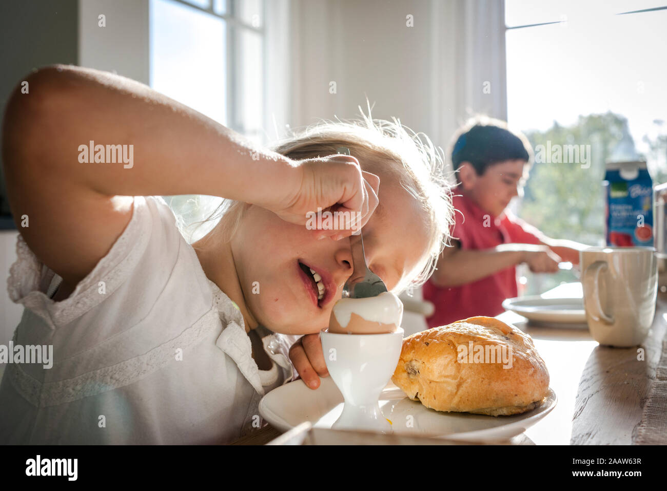 Mädchen mit einem gekochten Ei an Esstisch Stockfoto
