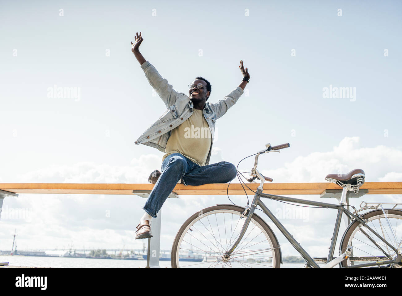 Junger Mann mit Fahrrad, sitzen auf railng durch das Meer, das so tut, als zu fliegen Stockfoto