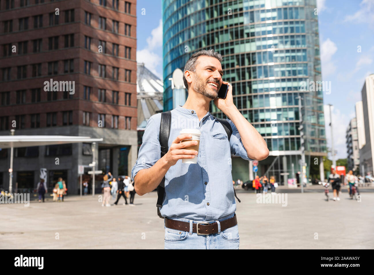 Lächelnd Geschäftsmann am Telefon zu sprechen in der Stadt, Berlin, Deutschland Stockfoto