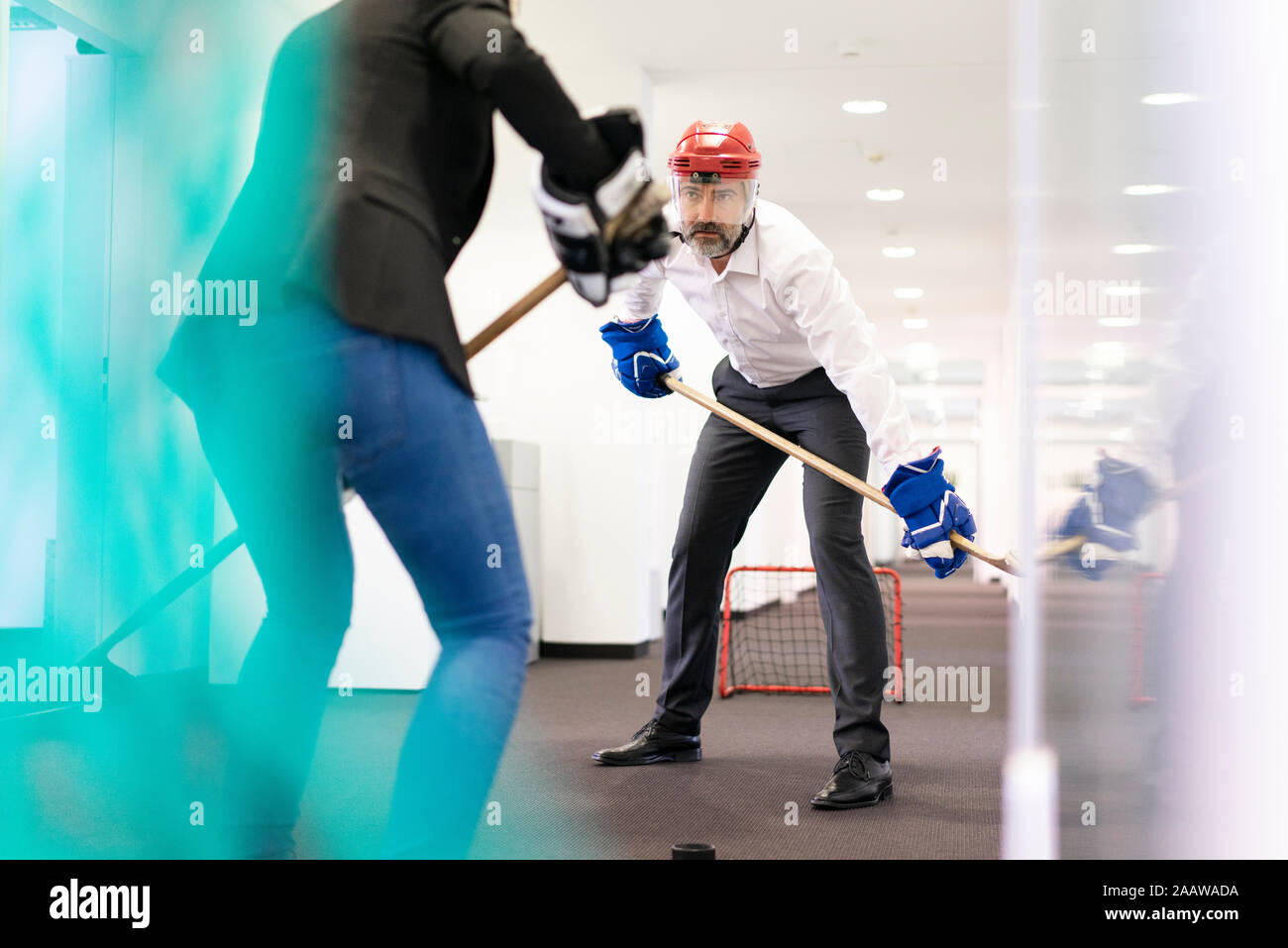 Business-frau und Geschäftsmann spielen Eishockey im Büro Stockfoto