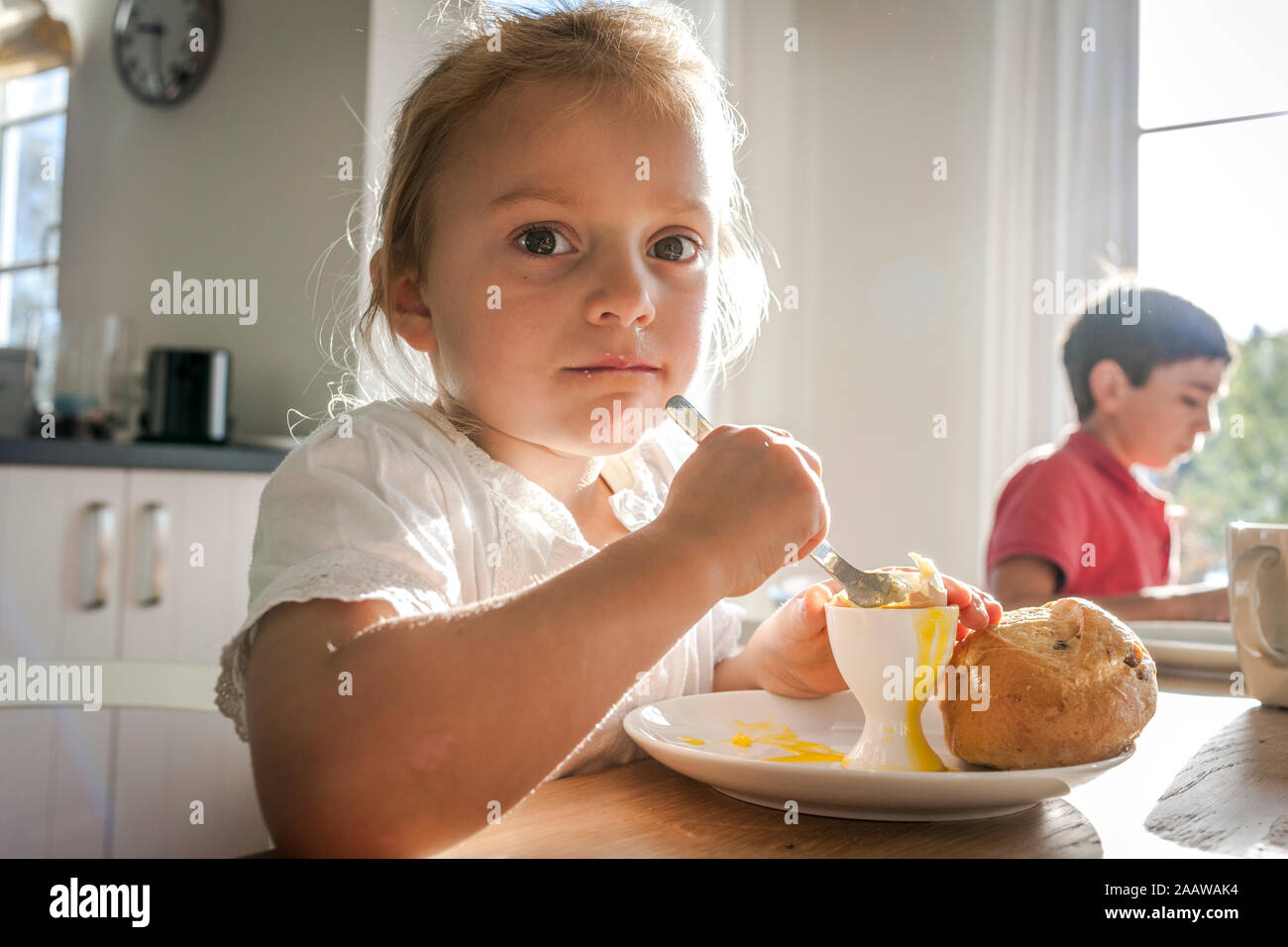 Portrait von Mädchen mit einem gekochten Ei an Esstisch Stockfoto